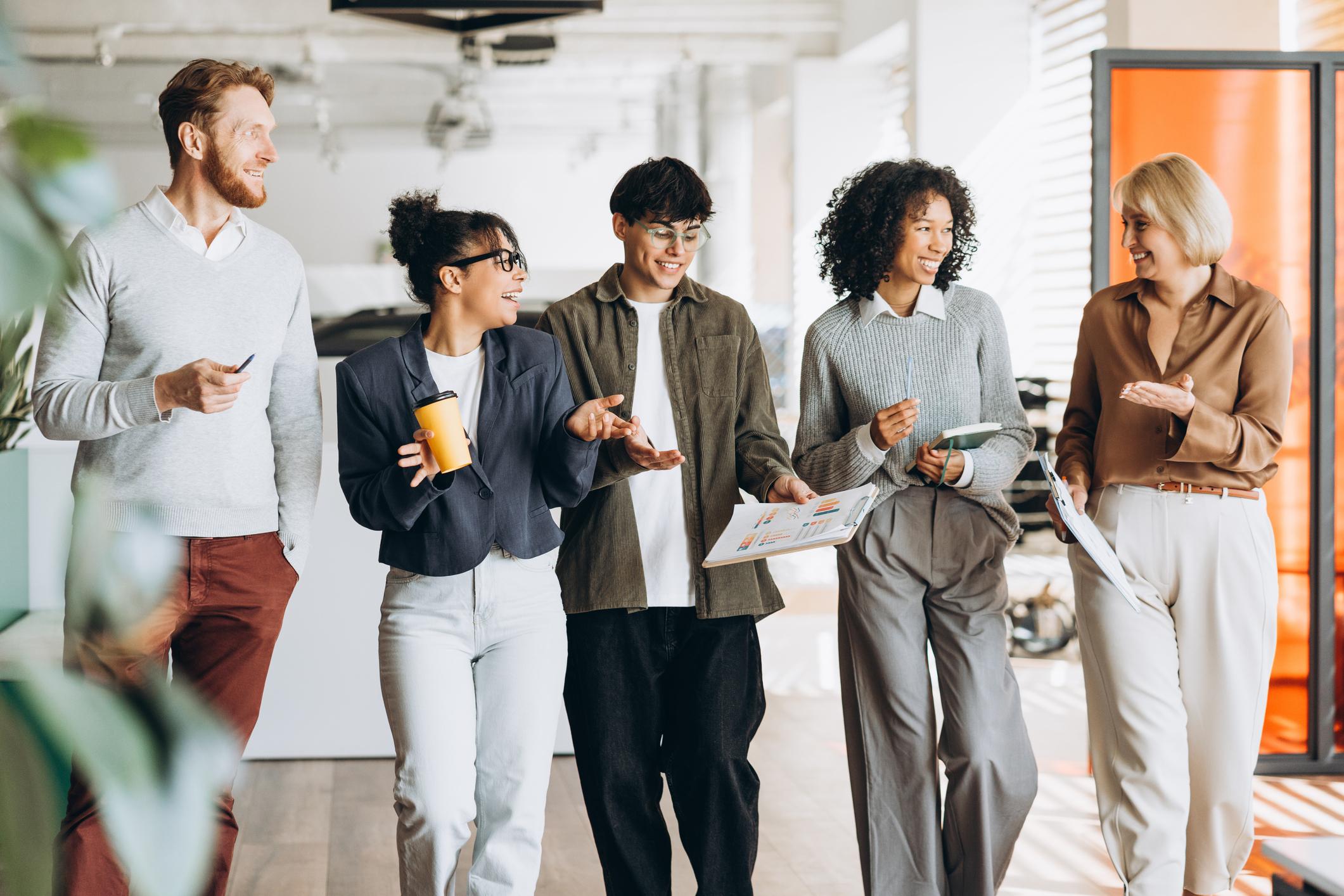 Successful positive team, diverse group walking talking together in modern office
